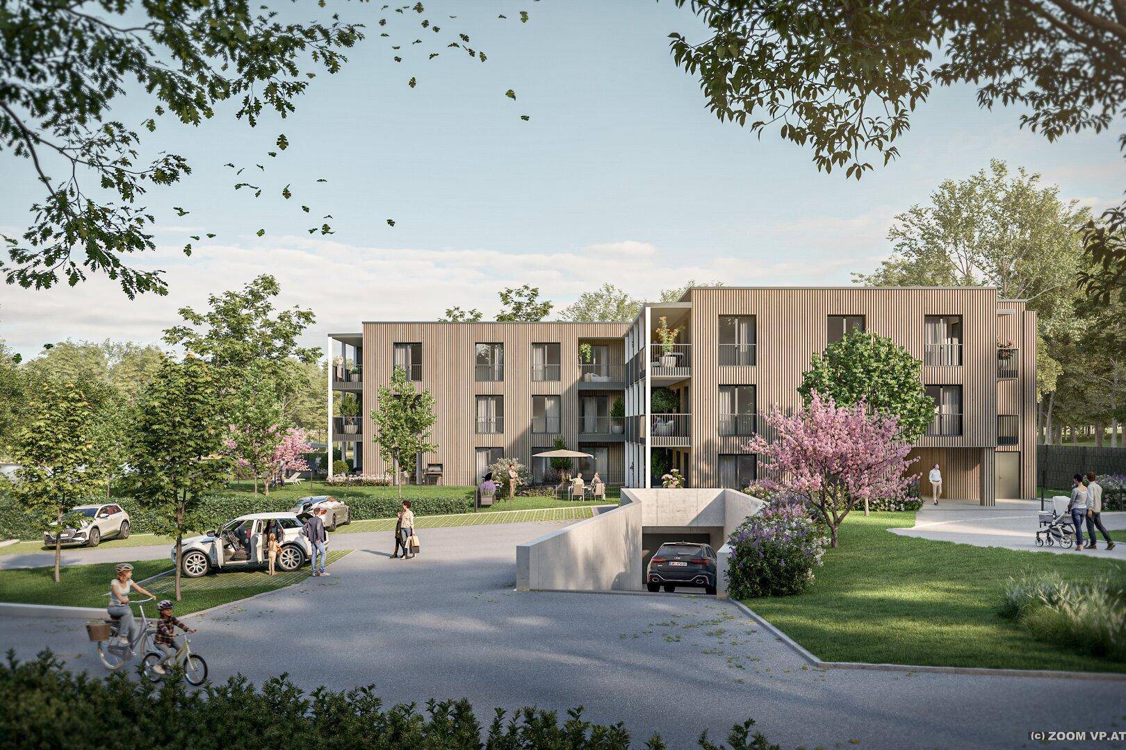Moderne Wohnanlage mit Tiefgaragenzufahrt und begrünten Außenbereichen.