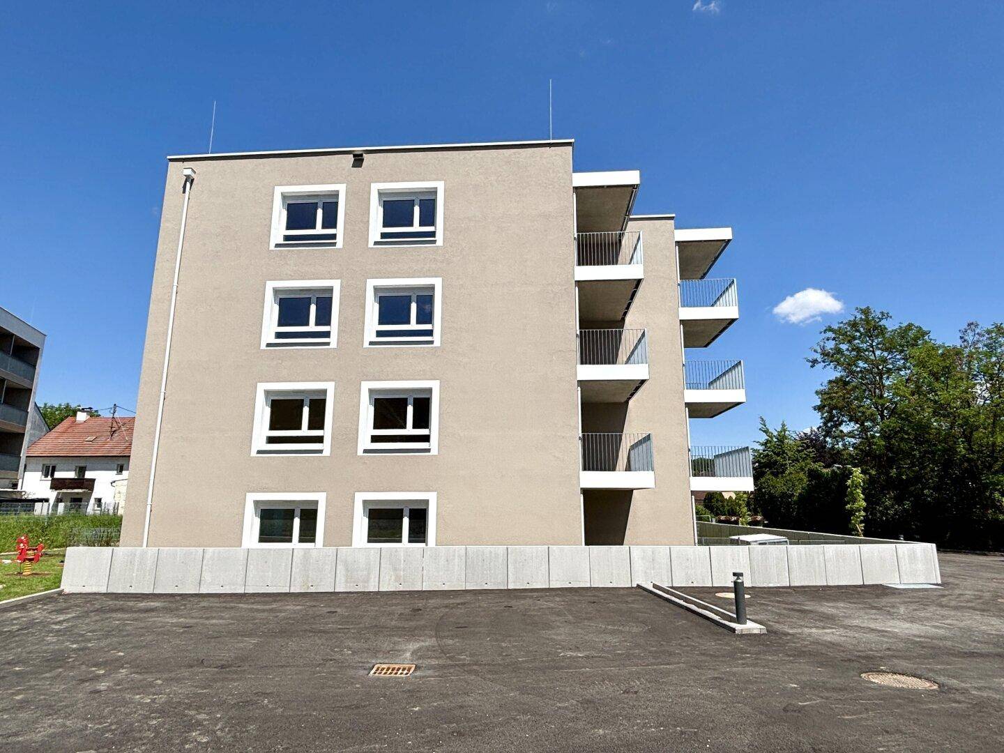 Seitenansicht eines modernen Wohngebäudes mit Balkonen und Außenbereich.