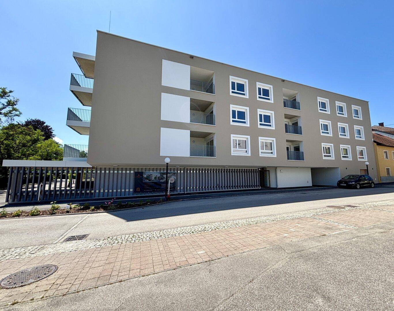 Moderne Wohnanlage mit Balkonen und Tiefgaragenzufahrt an einer ruhigen Straße gelegen.
