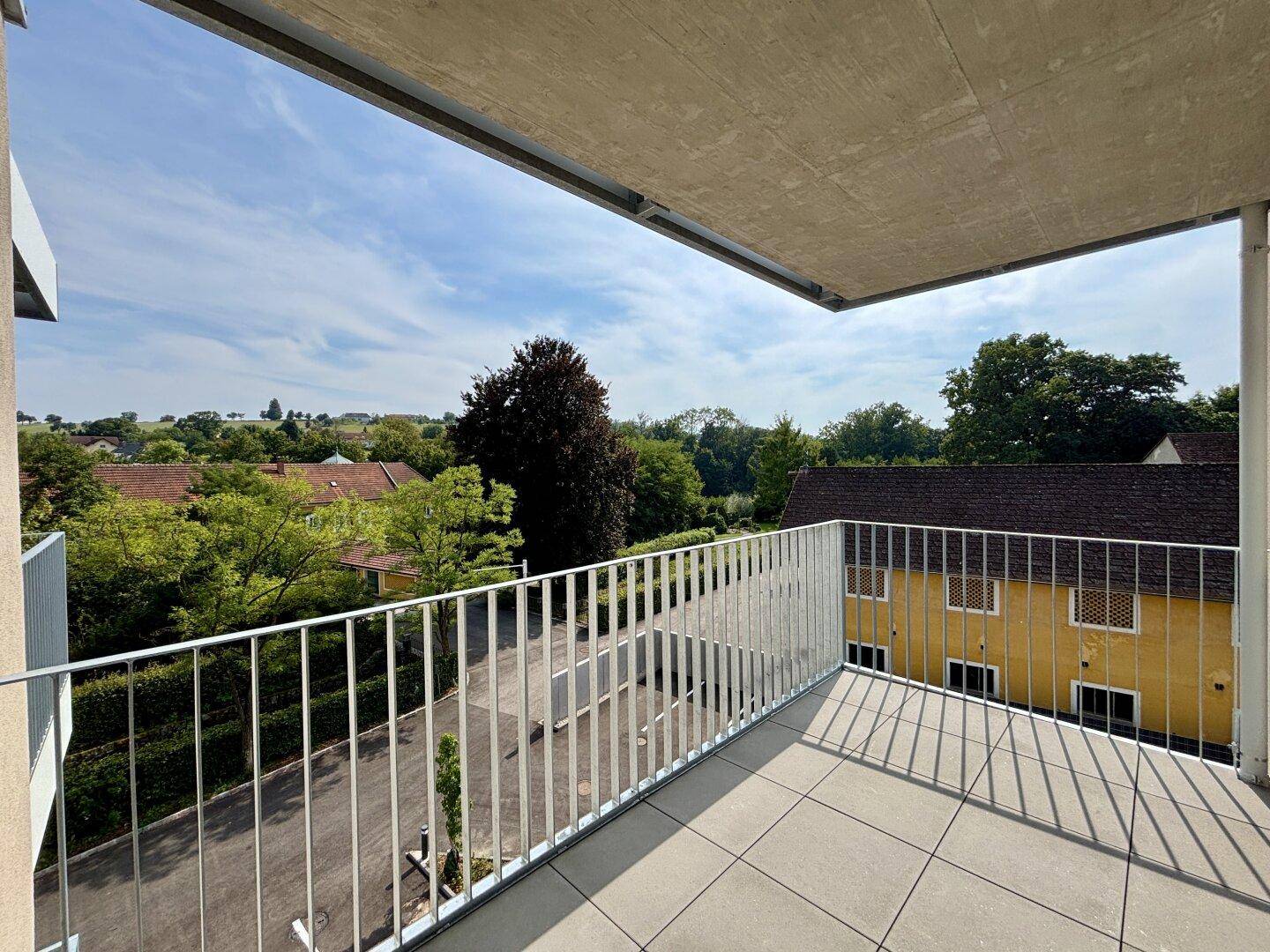 Geräumiger Balkon mit Fliesenboden und weitem Blick über die grüne Umgebung.