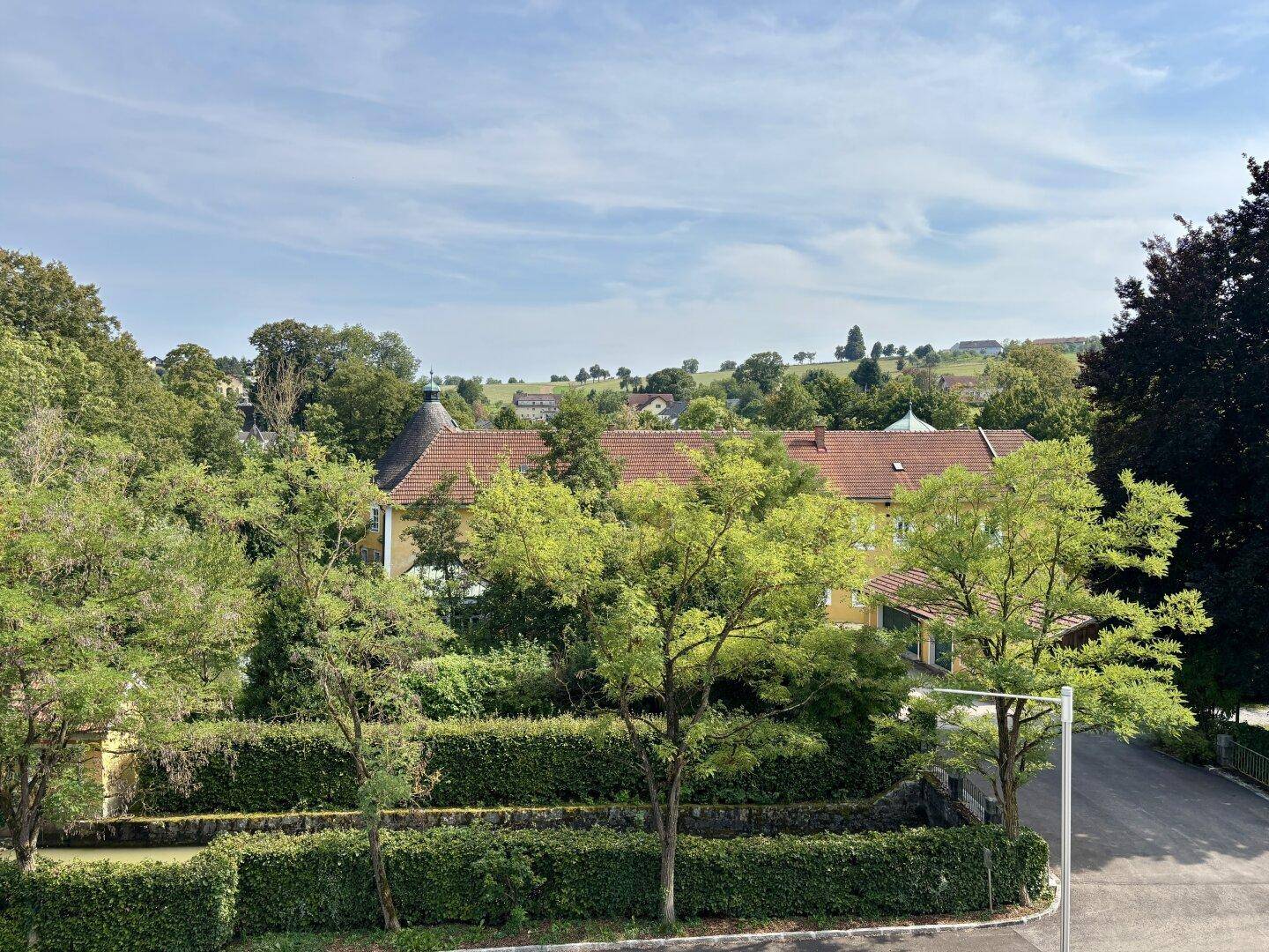 Weitläufiger Blick über eine grüne Landschaft mit Häusern und Hügeln.