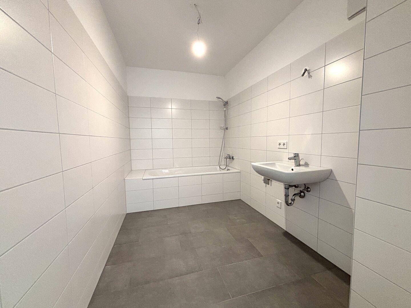Modernes Badezimmer mit weißen Fliesen, Badewanne und Waschbecken.