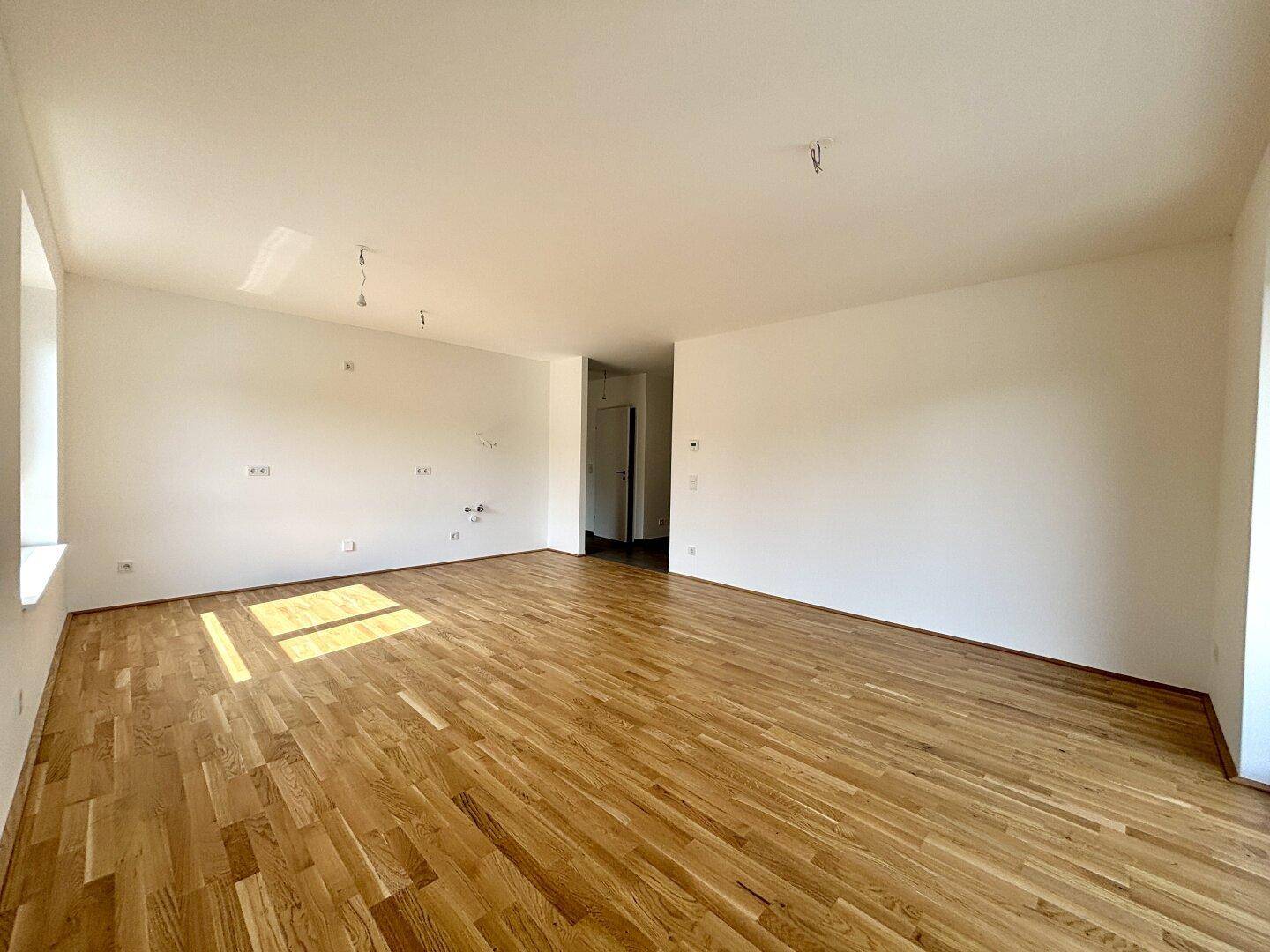 Geräumiger, heller Wohnbereich mit Eichenparkett und weißen Wänden, bereit zur individuellen Gestaltung.