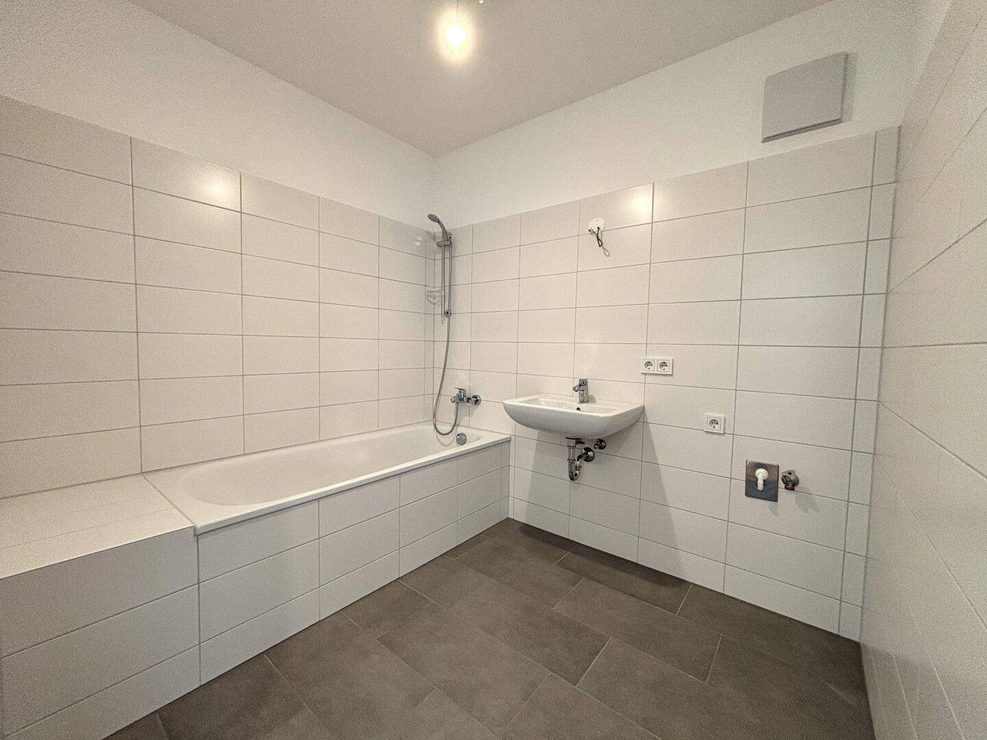 Modernes Badezimmer mit weiß gefliesten Wänden, Badewanne und Einzelwaschbecken.