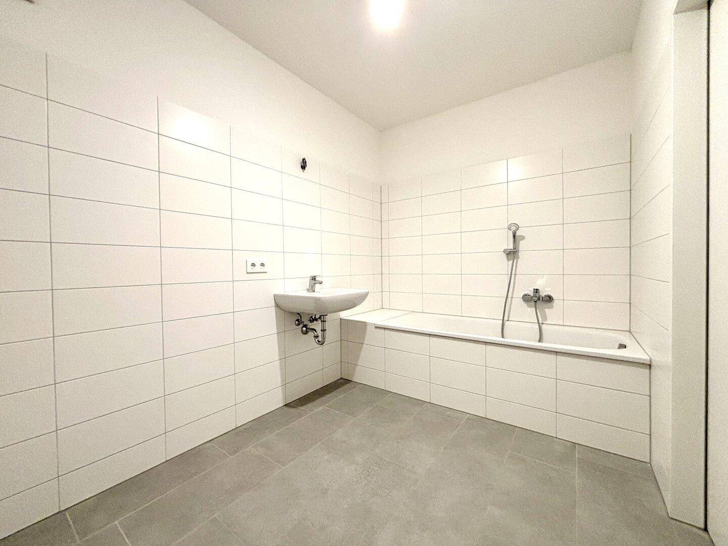 Modernes Badezimmer mit weißen Fliesen, einem Waschbecken und einer Badewanne, bereit zur individuellen Gestaltung.