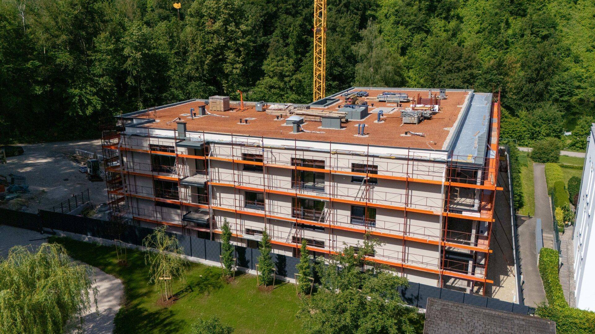 Nahaufnahme des im Bau befindlichen Gebäudes mit Gerüst und moderner Fassadengestaltung.