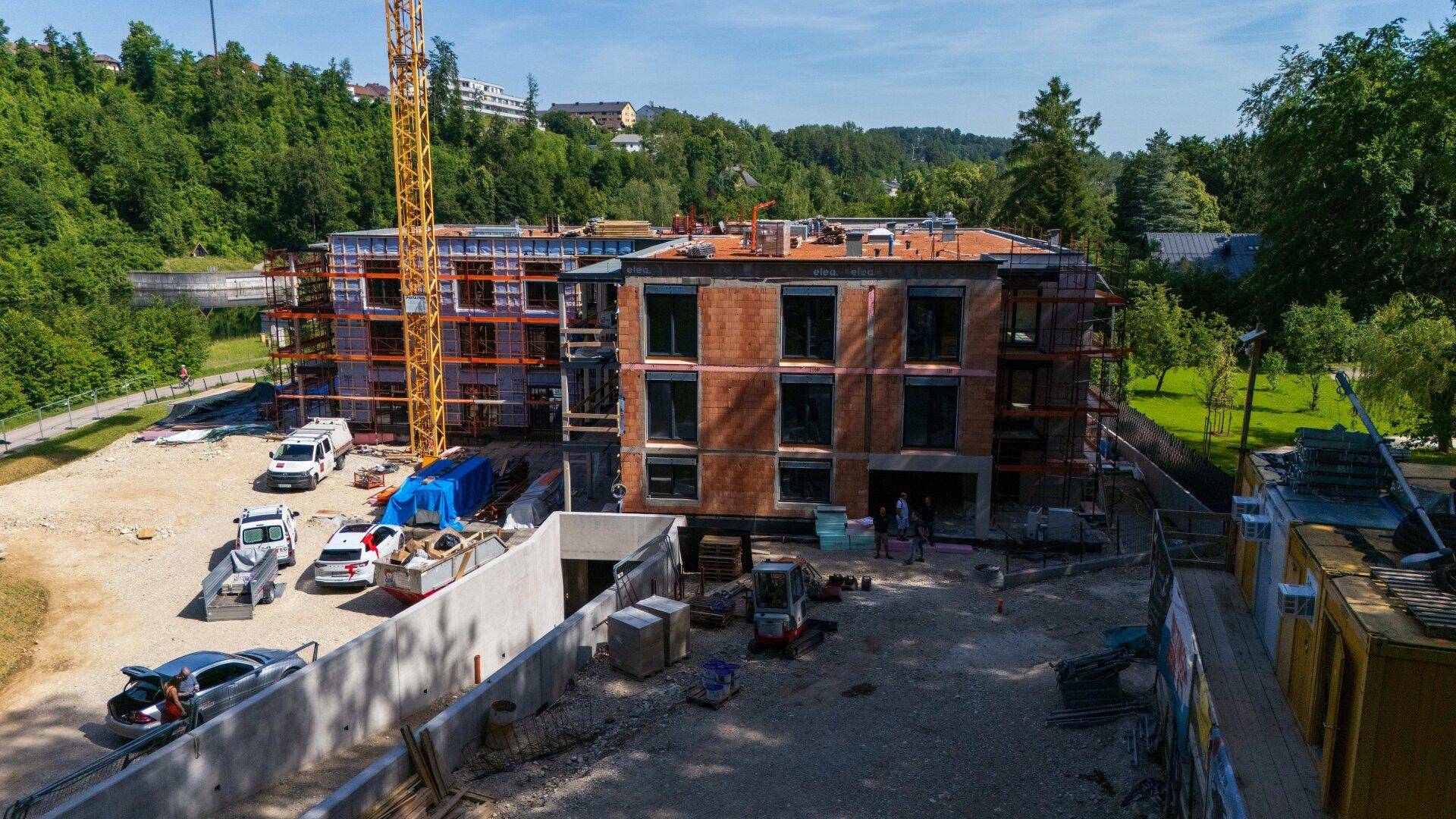 Nahaufnahme einer Baustelle mit einem im Bau befindlichen Gebäude und einem Kran unter blauem Himmel.