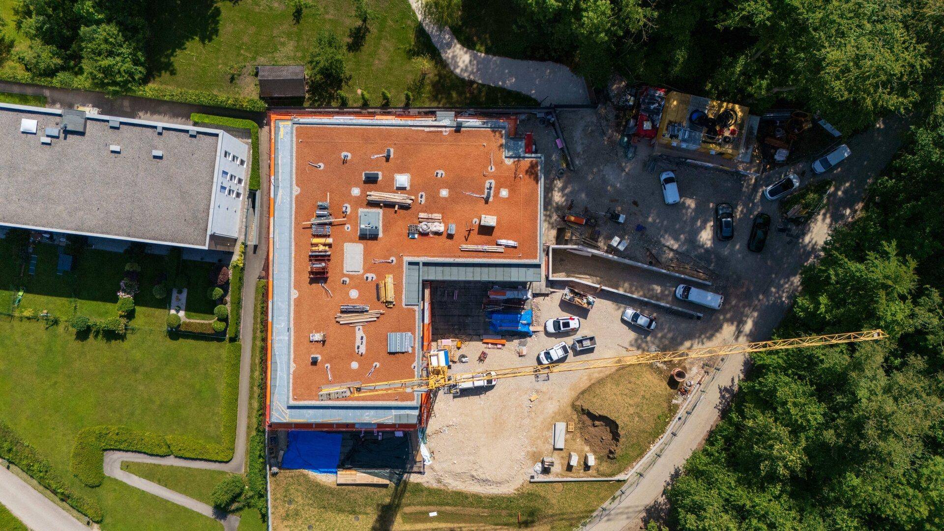 Vogelperspektive des im Bau befindlichen Gebäudes, zeigt das Flachdach und die Baustelle von oben.