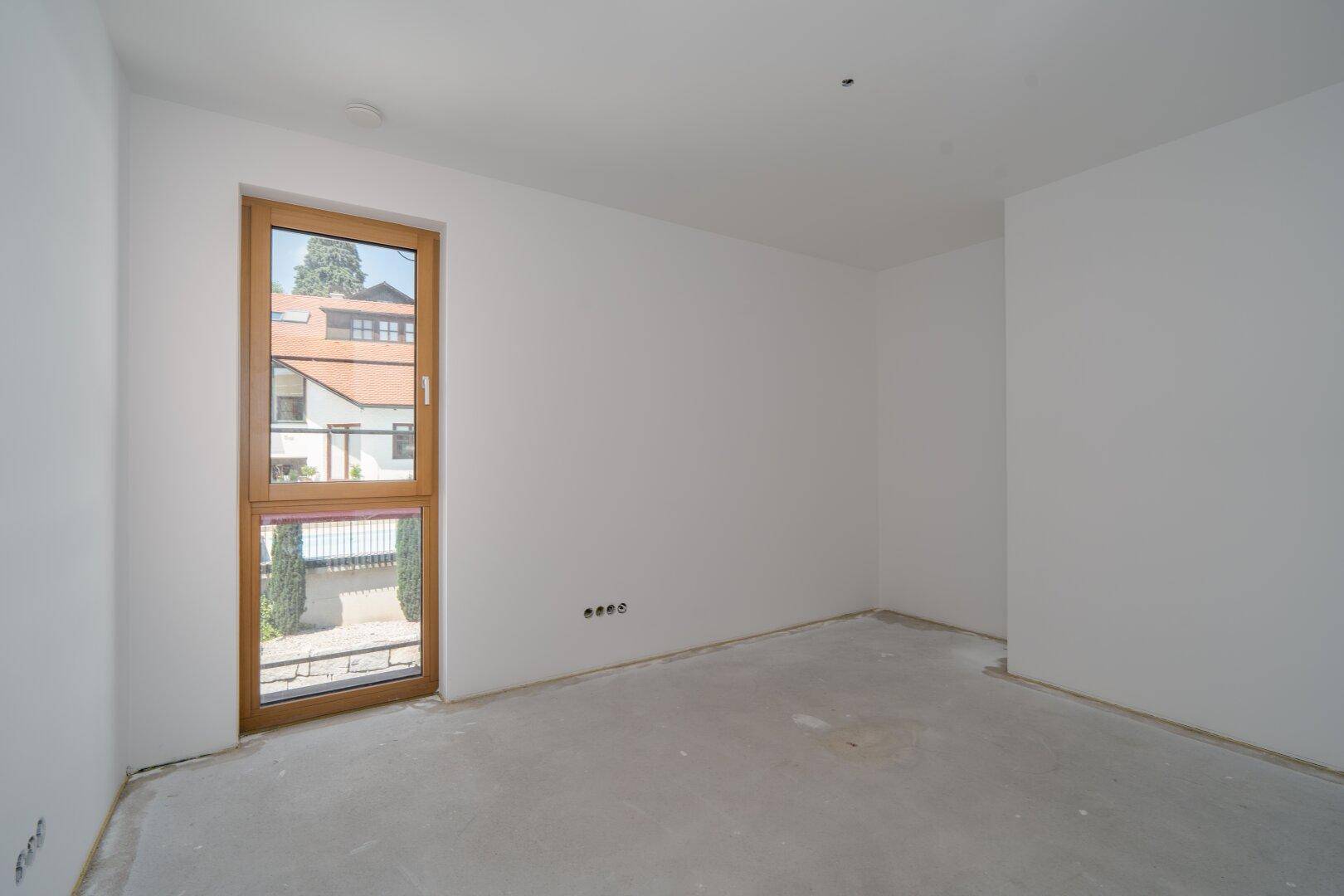 Leerer Raum mit einem hohen Fenster und weiß gestrichenen Wänden, noch unfertig.