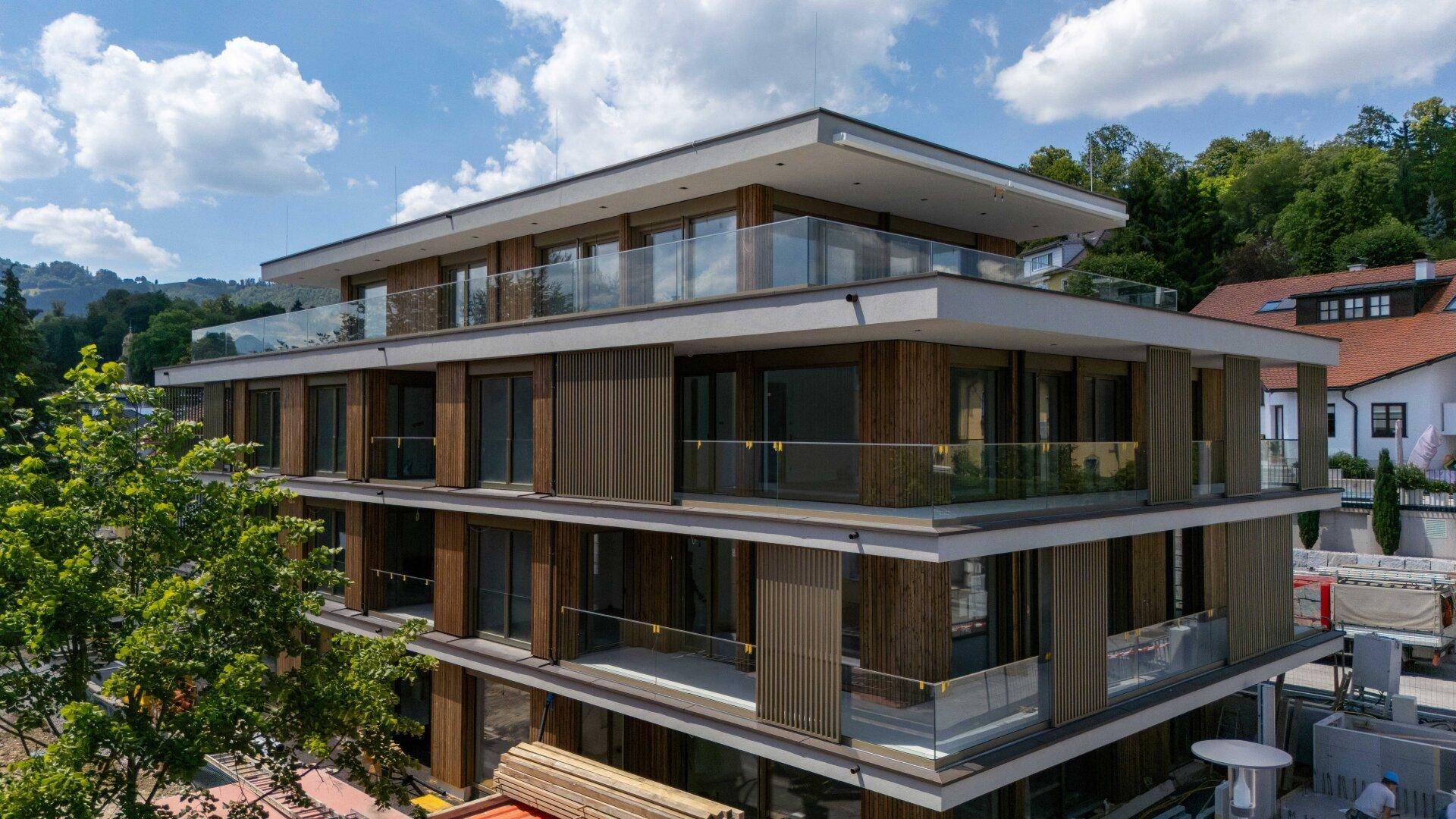Moderne Architektur eines Mehrfamilienhauses mit Holzfassade und großzügigen Balkonen.