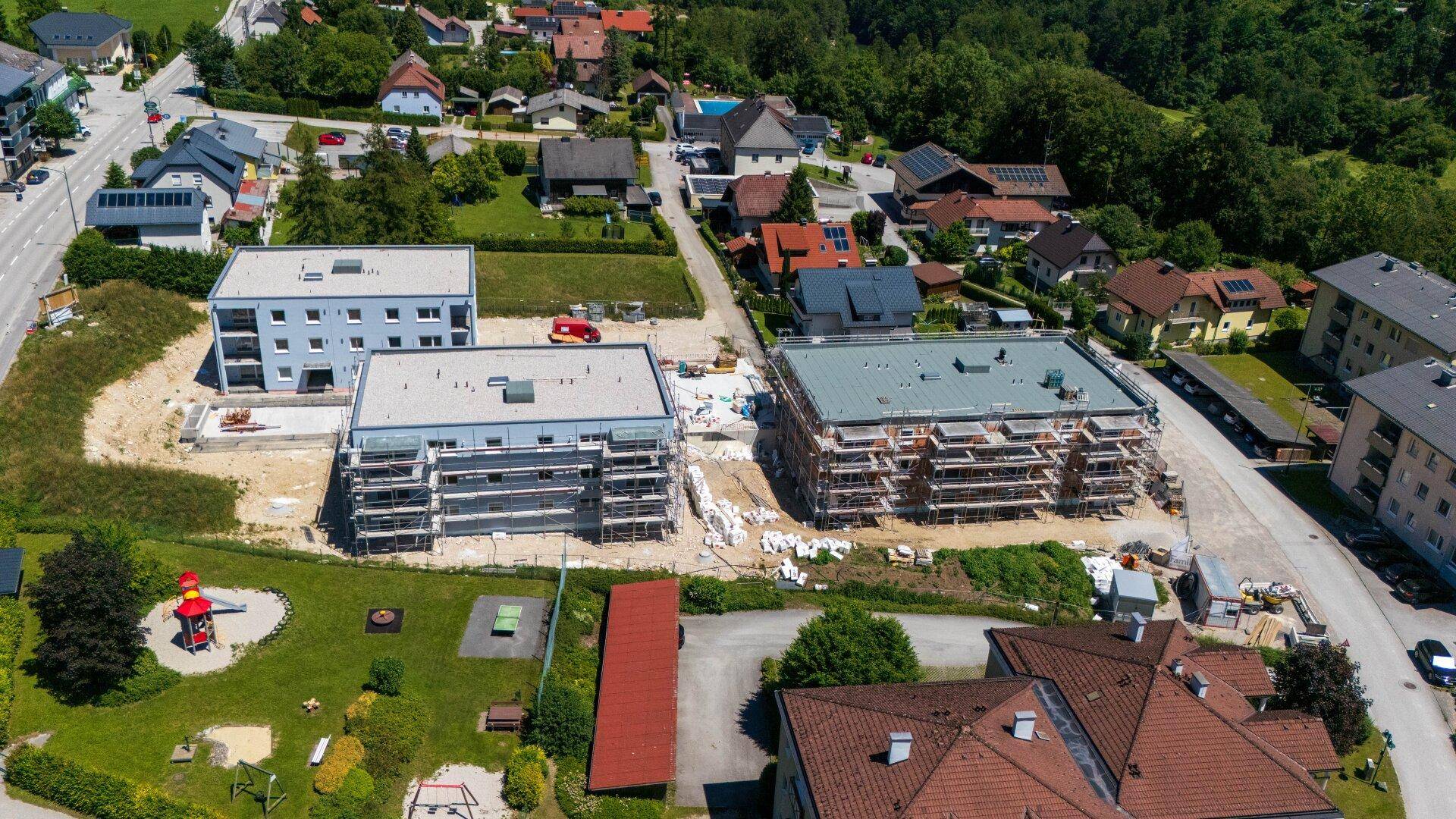 Luftaufnahme von Neubauprojekten mit Spielplatz in einer Wohnsiedlung mit Bergblick.