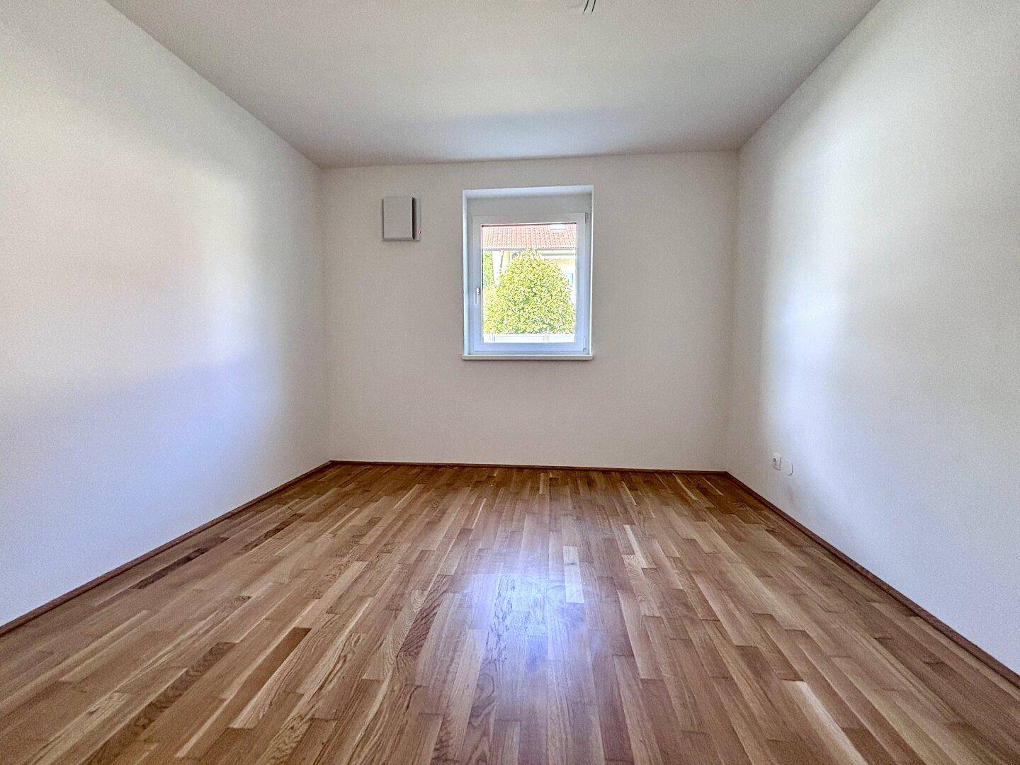 Helles Zimmer mit Parkettboden und weiß gestrichenen Wänden, vielseitig nutzbar als Schlaf- oder Arbeitszimmer.