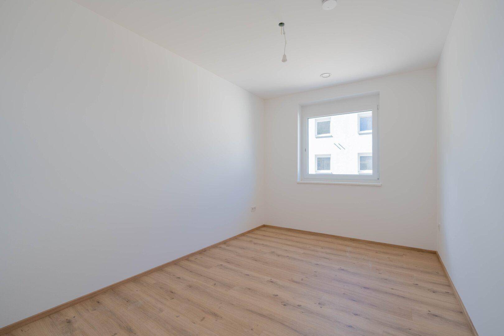 Geräumiges Zimmer mit Laminatboden und weiß gestrichenen Wänden, ideal als Schlaf- oder Arbeitszimmer.