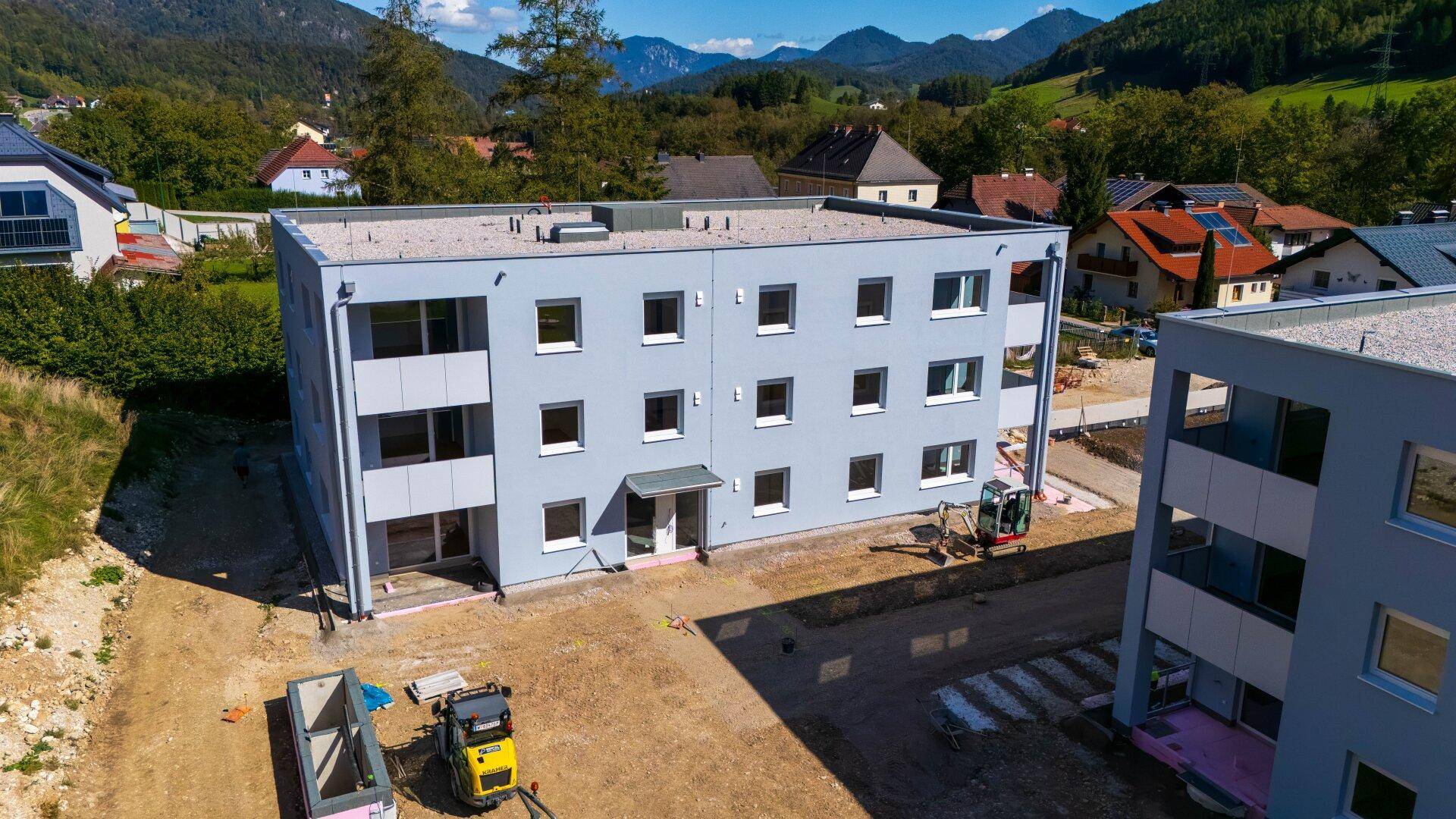 Neubau eines modernen Mehrfamilienhauses in ländlicher Umgebung mit Baustelle.