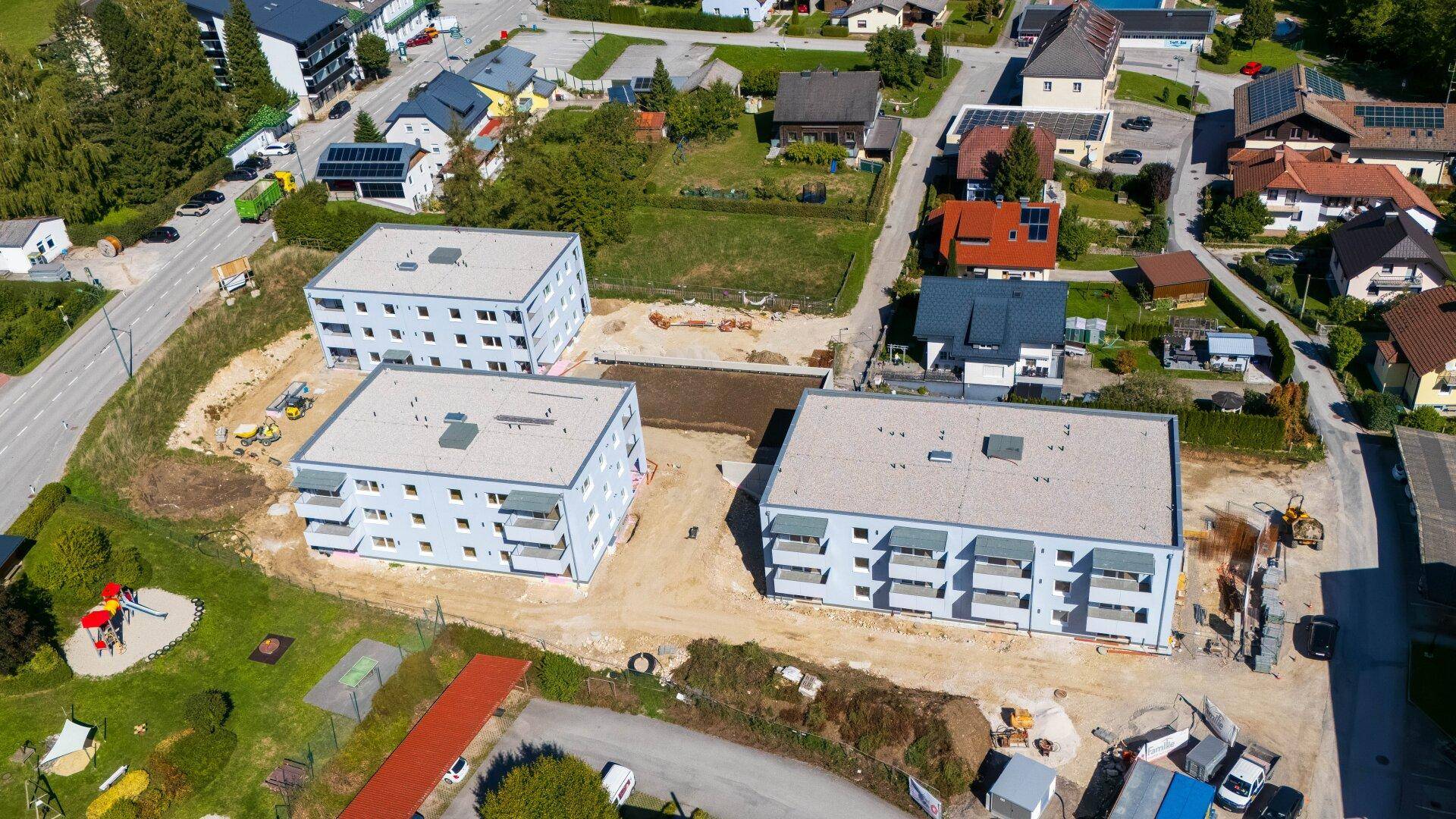 Luftaufnahme der drei im Bau befindlichen Mehrfamilienhäuser in einer ländlichen Umgebung.