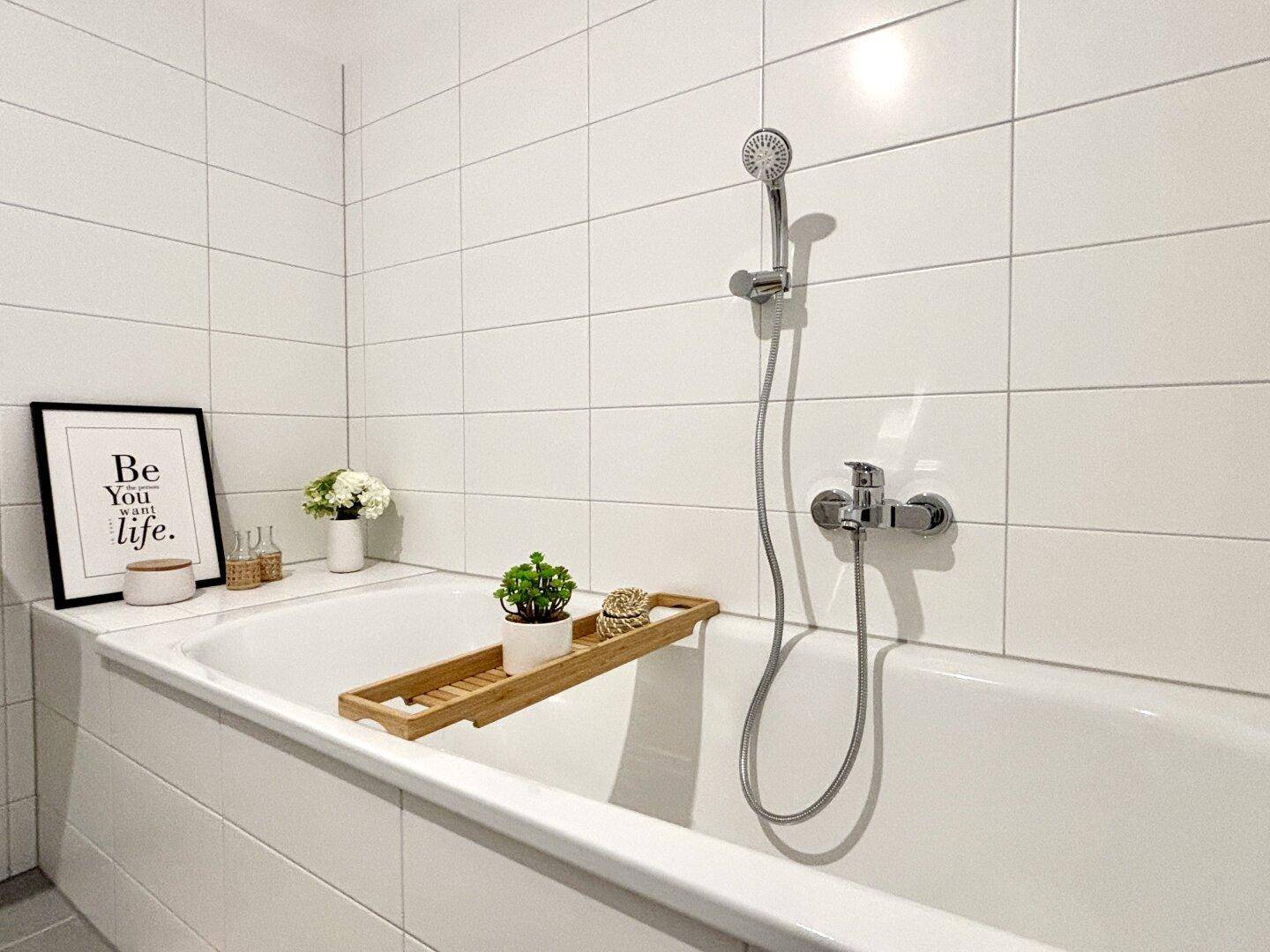 Modernes Badezimmer mit weiß gefliesten Wänden und einer integrierten Badewanne mit Duschfunktion.