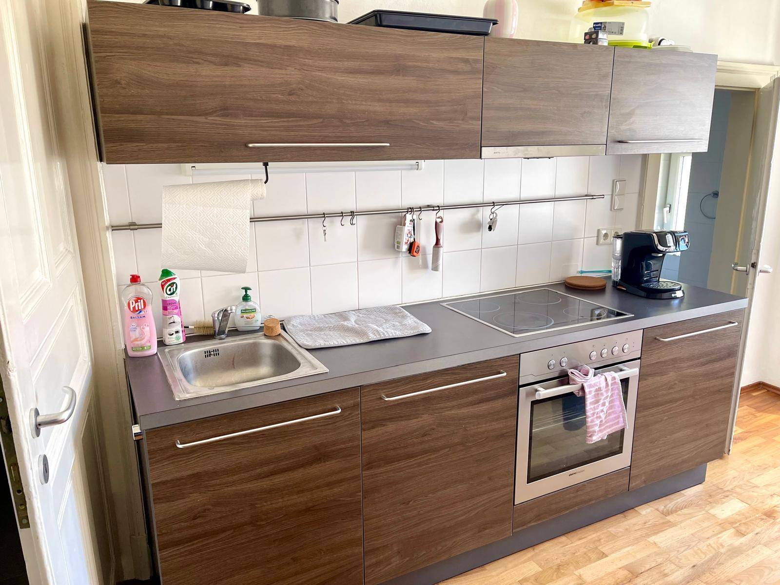 Moderne Küchenzeile mit Holzfronten, Spüle, Kochfeld und Backofen.