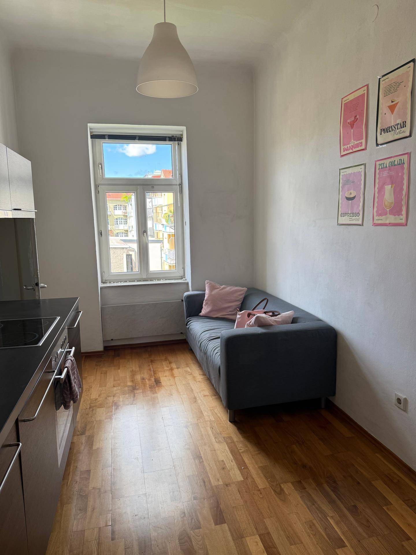 Heller Wohnbereich mit Sofa, Holzboden und Blick aus dem Fenster auf die Umgebung.