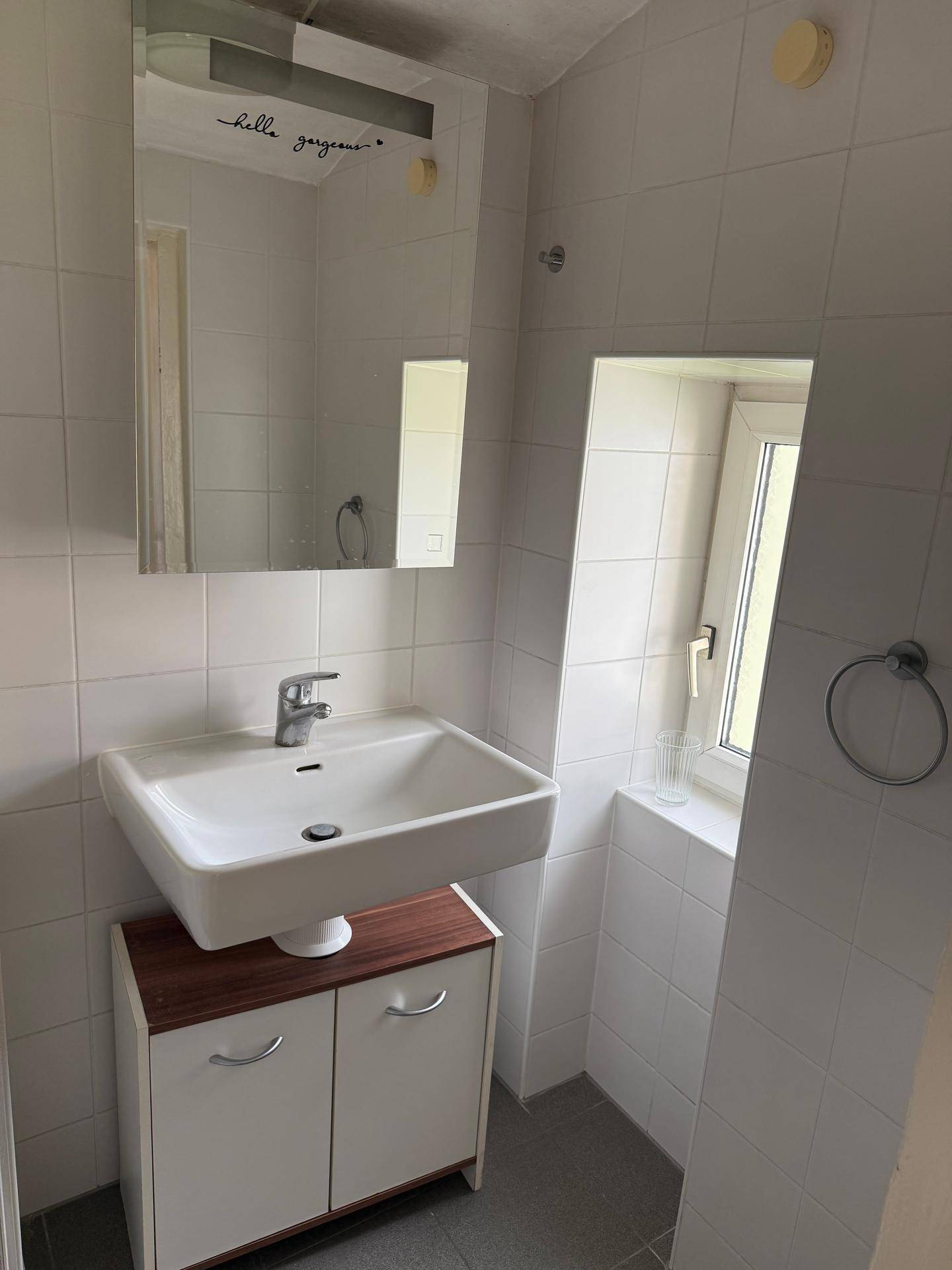 Badezimmer mit Waschbecken, Spiegelschrank und Fenster für Tageslicht.