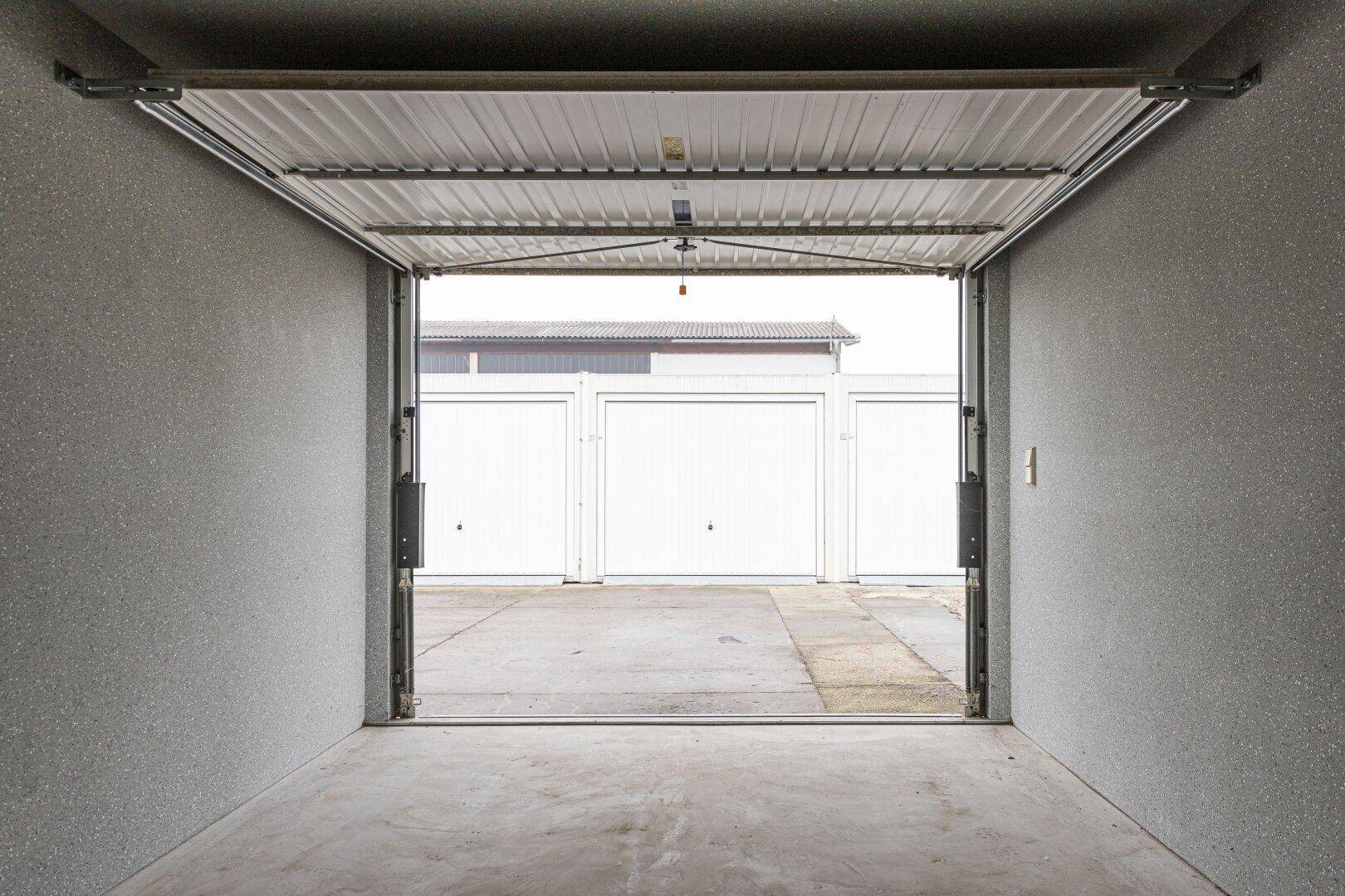 Blick aus einer Einzelgarage auf weitere Garagen und einen asphaltierten Vorplatz.