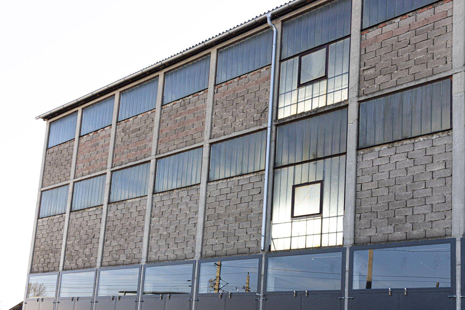 Detailansicht der Gebäudefassade mit einer Kombination aus Betonblöcken und großen, reflektierenden Glasfenstern.