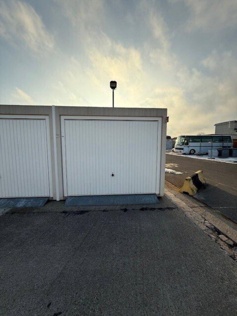 Außenansicht einer einzelnen Garage mit weißem Tor unter einem hellen Himmel.