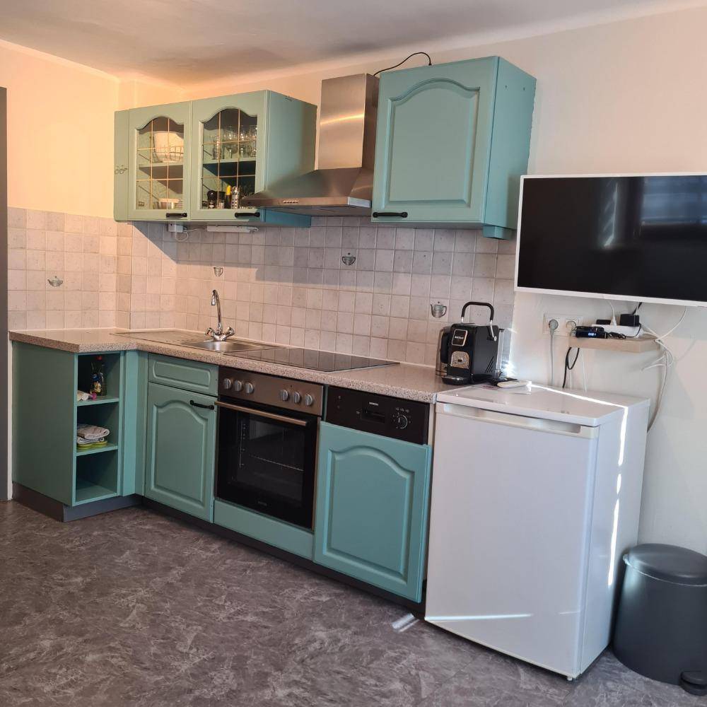 Traditionelle Küche mit mintgrünen Schränken, weißen Fliesen und integrierten Geräten.