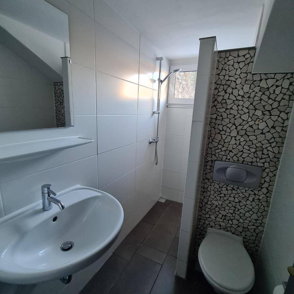Modernes Badezimmer mit weißem Waschbecken, Dusche und dekorativen Mosaikfliesen.