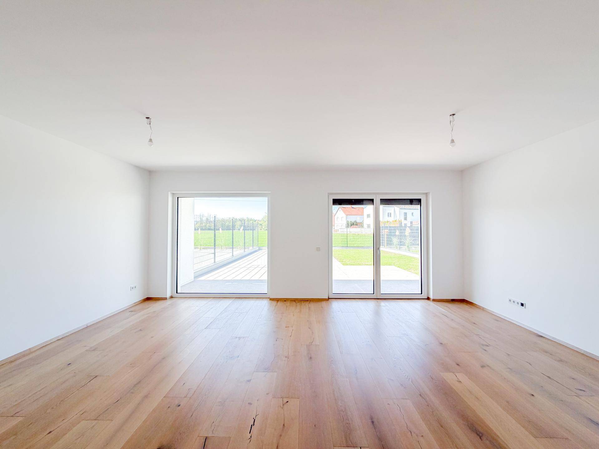 Geräumiges Wohnzimmer mit Eichenparkett und großen Schiebetüren zur Terrasse.