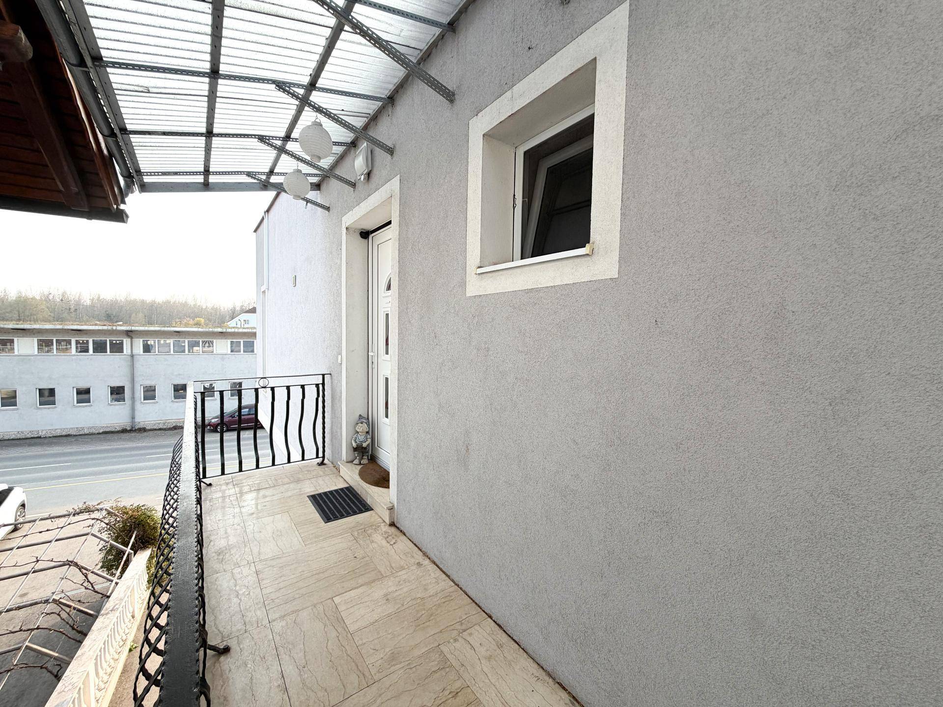 Überdachter Balkon mit Fliesenboden und schmiedeeisernem Geländer.