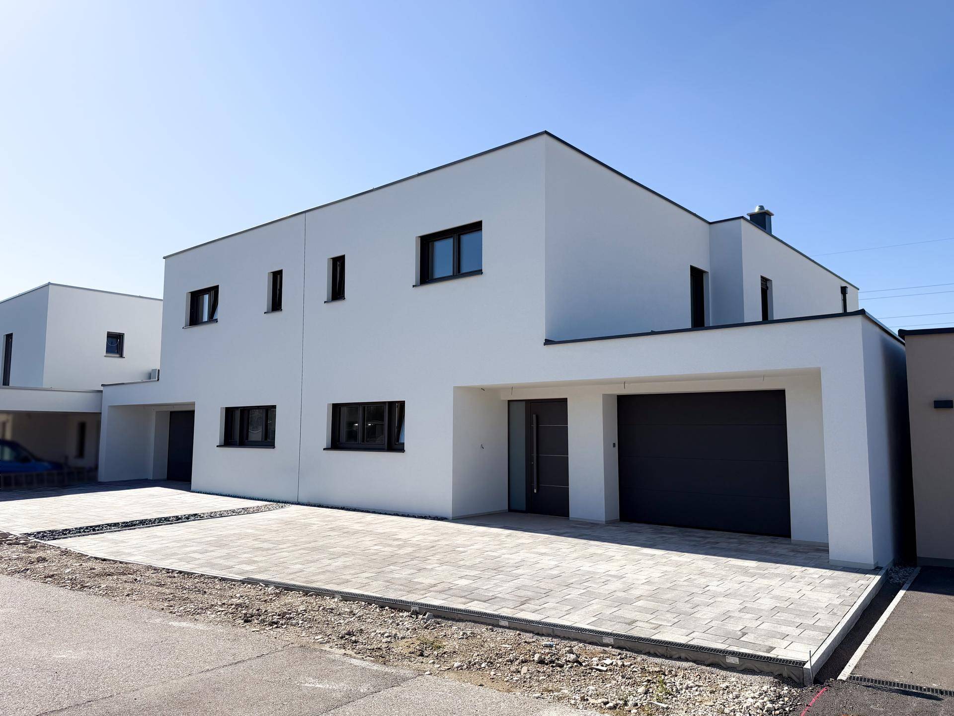 Elegantes Einfamilienhaus mit moderner Architektur, Garage und gepflasterter Auffahrt.