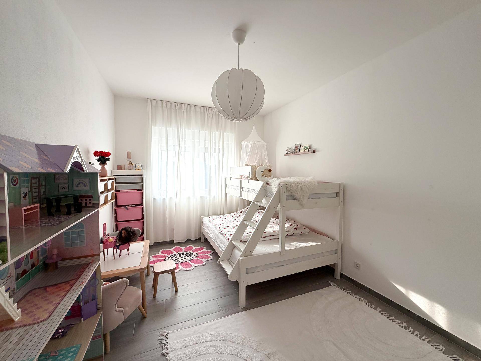 Freundliches Kinderzimmer mit Etagenbett, Spielzeug und hellem Teppich.