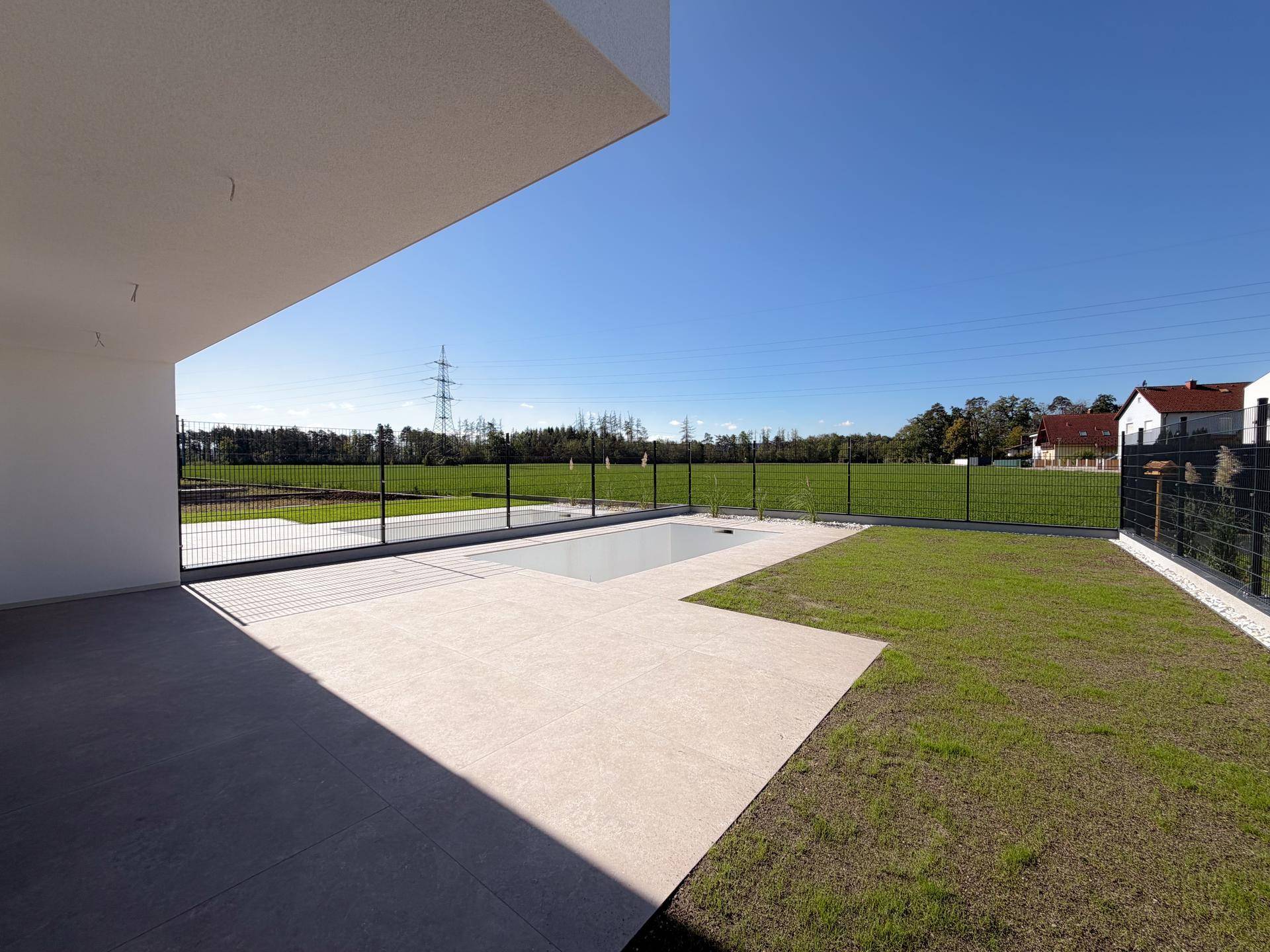 Geräumige Terrasse mit direktem Zugang zum Pool und weitem Blick ins Grüne.
