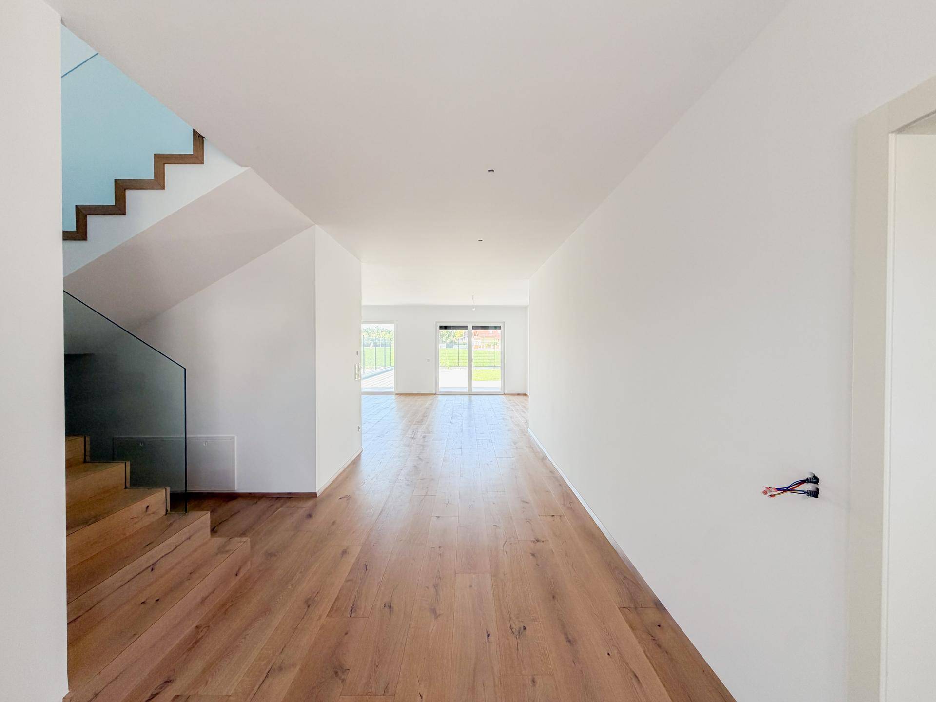 Heller Eingangsbereich mit moderner Holztreppe, Glasgeländer und Eichenparkettboden.