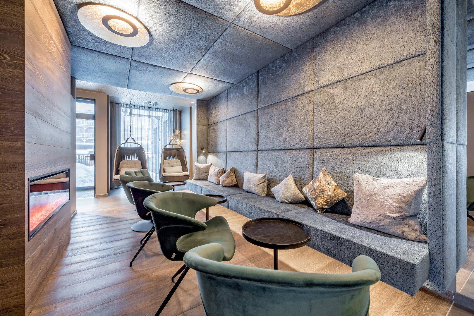 Stilvoller Loungebereich mit gepolsterten Wänden, bequemen Sitzgelegenheiten und modernem Kamin für Gemütlichkeit.