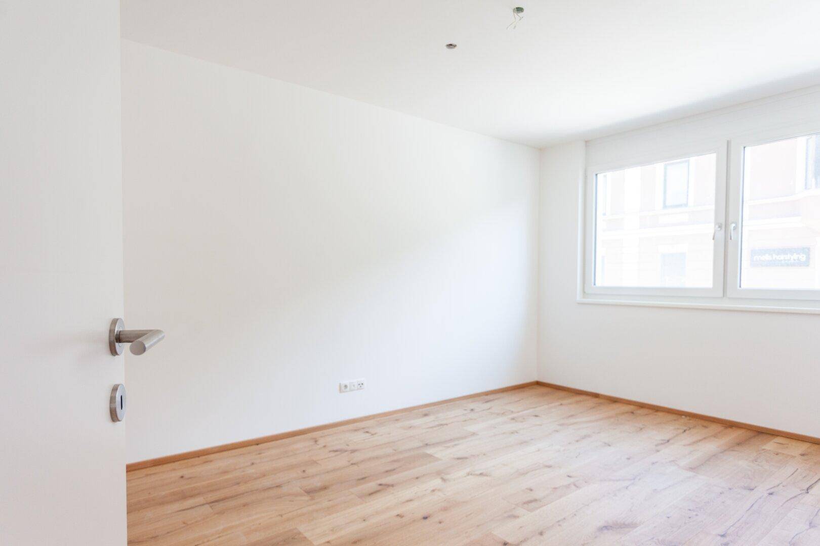 Leeres Schlafzimmer mit Holzboden und Fenster, ideal für individuelle Gestaltung.