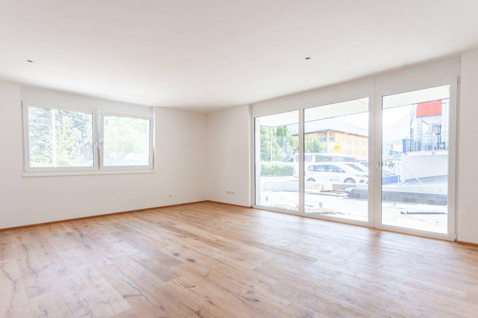Geräumiger, heller Wohnbereich mit großen Schiebetüren und Holzboden, viel Tageslicht.