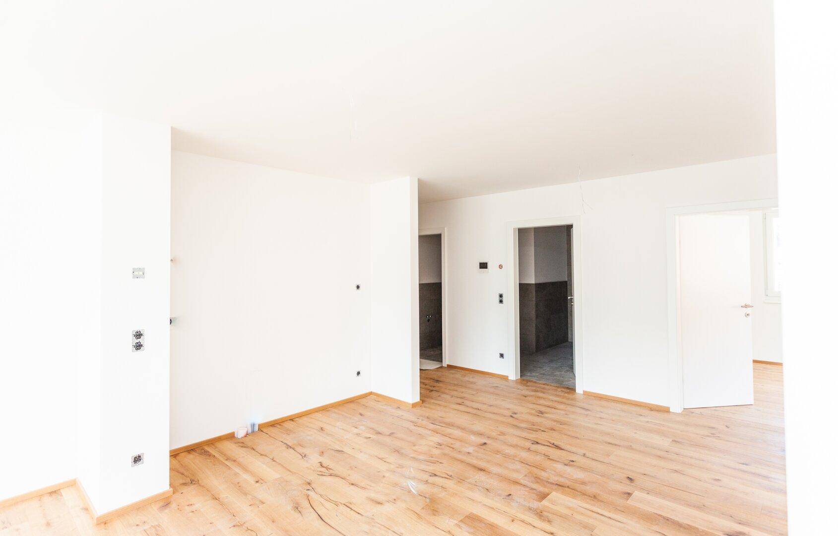 Geräumiger, unmöblierter Raum mit hellem Holzboden und weißen Wänden, ideal für individuelle Gestaltung.