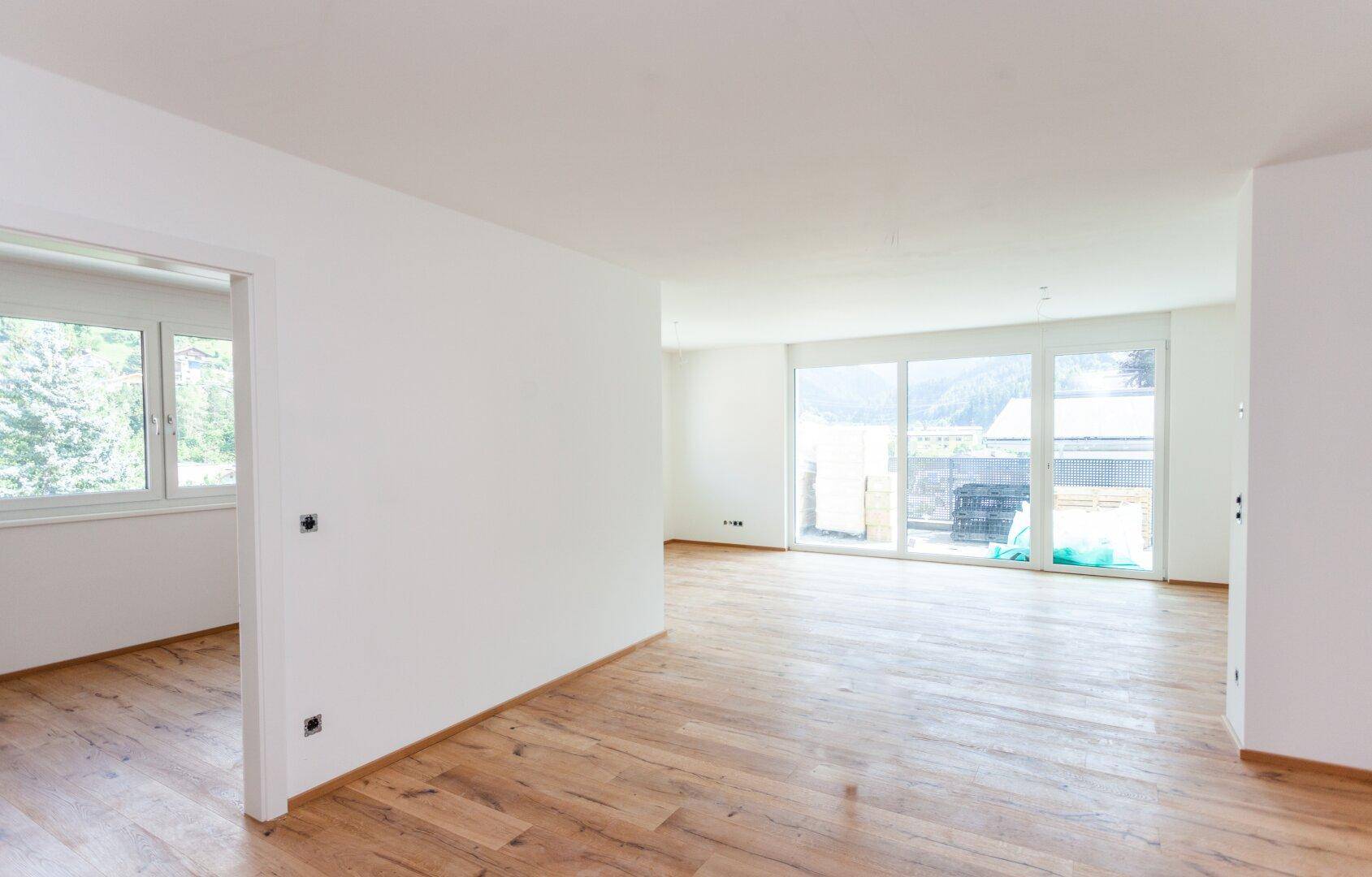 Lichtdurchfluteter Wohnbereich mit Holzboden und großen Schiebetüren zum Außenbereich.