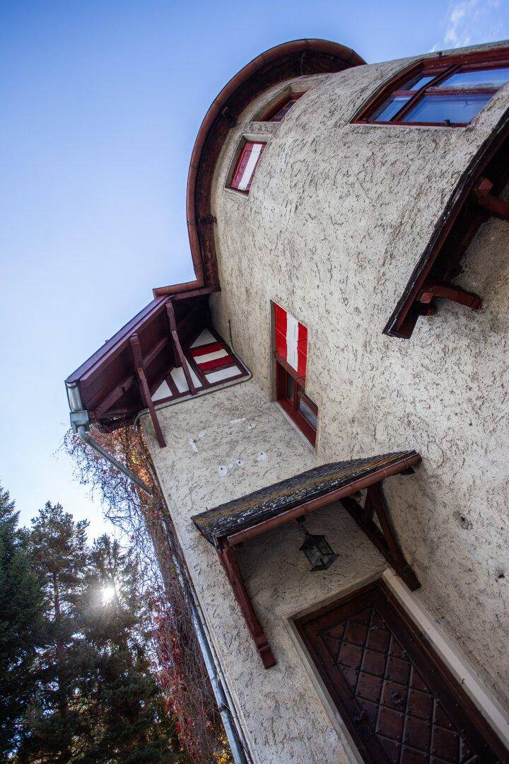 Vertikale Ansicht der historischen Fassade mit Holzelementen und roten Fensterläden unter blauem Himmel.