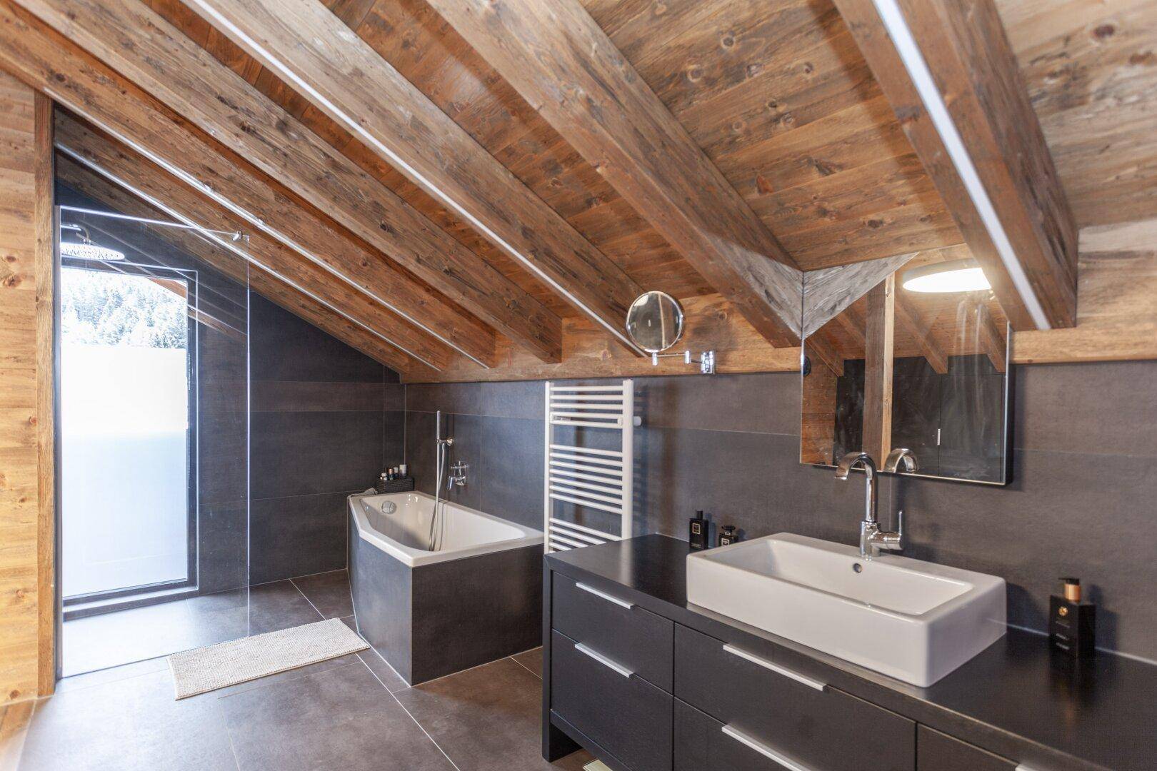 Elegantes Badezimmer mit Badewanne, modernem Waschbecken und beheiztem Handtuchhalter.
