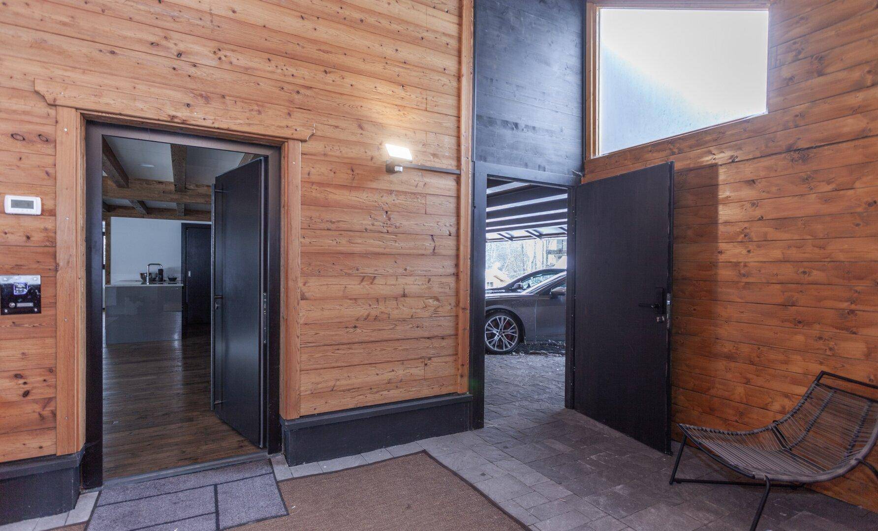 Eingangsbereich mit Holzwänden und direktem Zugang zum Carport.