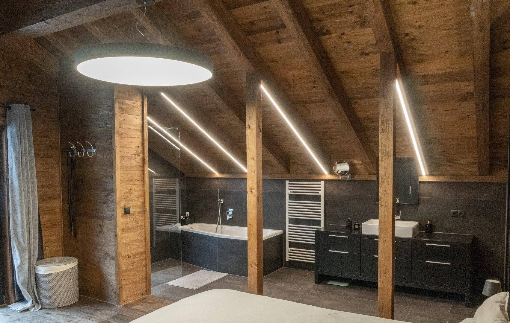 Modernes Badezimmer im Schlafzimmer mit Badewanne, Doppelwaschbecken und beheiztem Handtuchhalter.