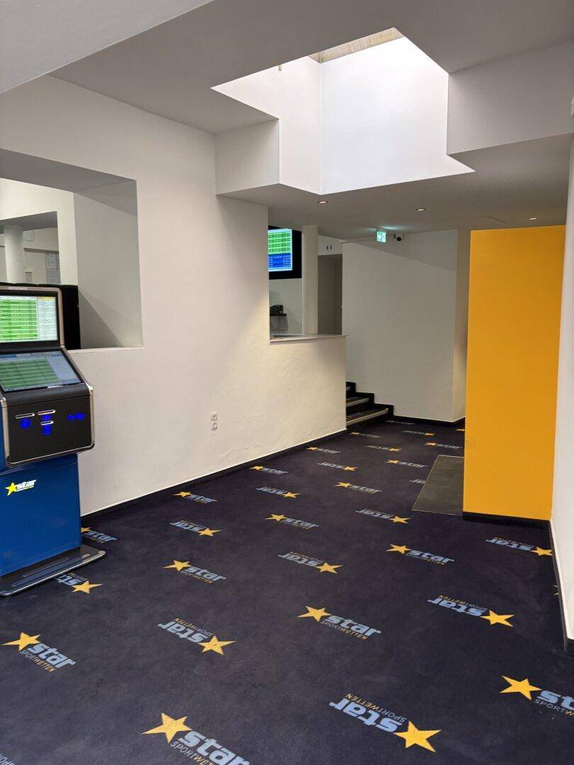 Heller Flur mit Oberlicht, einem Wettterminal und einer Treppe im Hintergrund, der zu weiteren Bereichen führt.