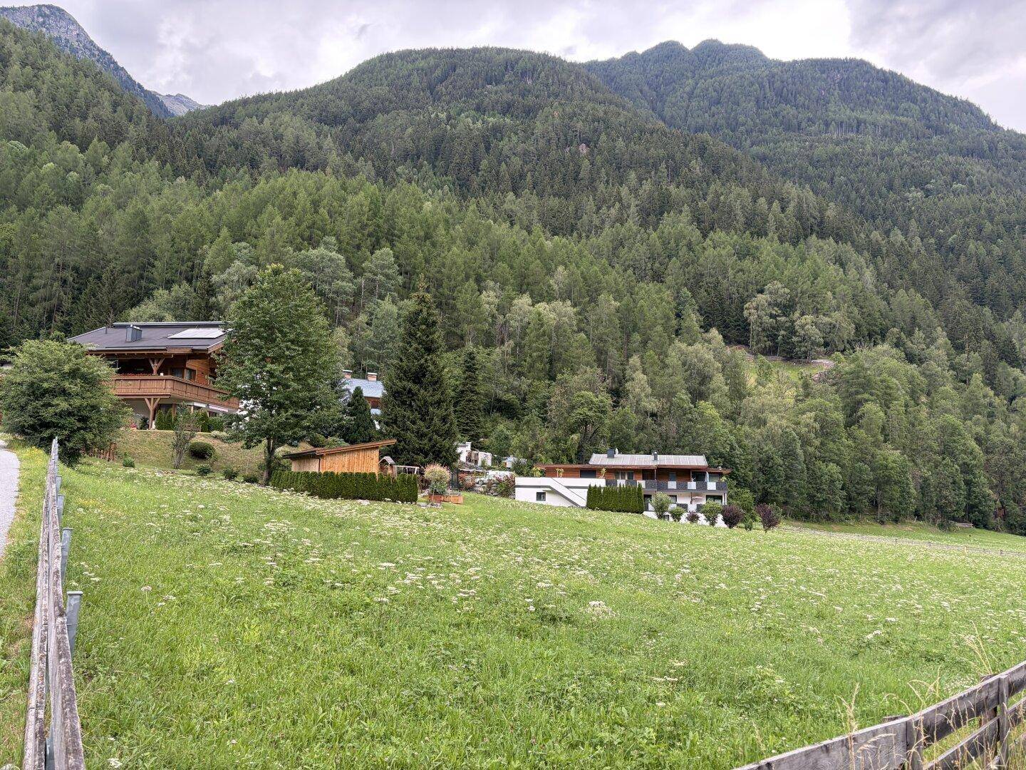Anwesen in idyllischer Berglandschaft mit weiten Wiesen und dichtem Wald.