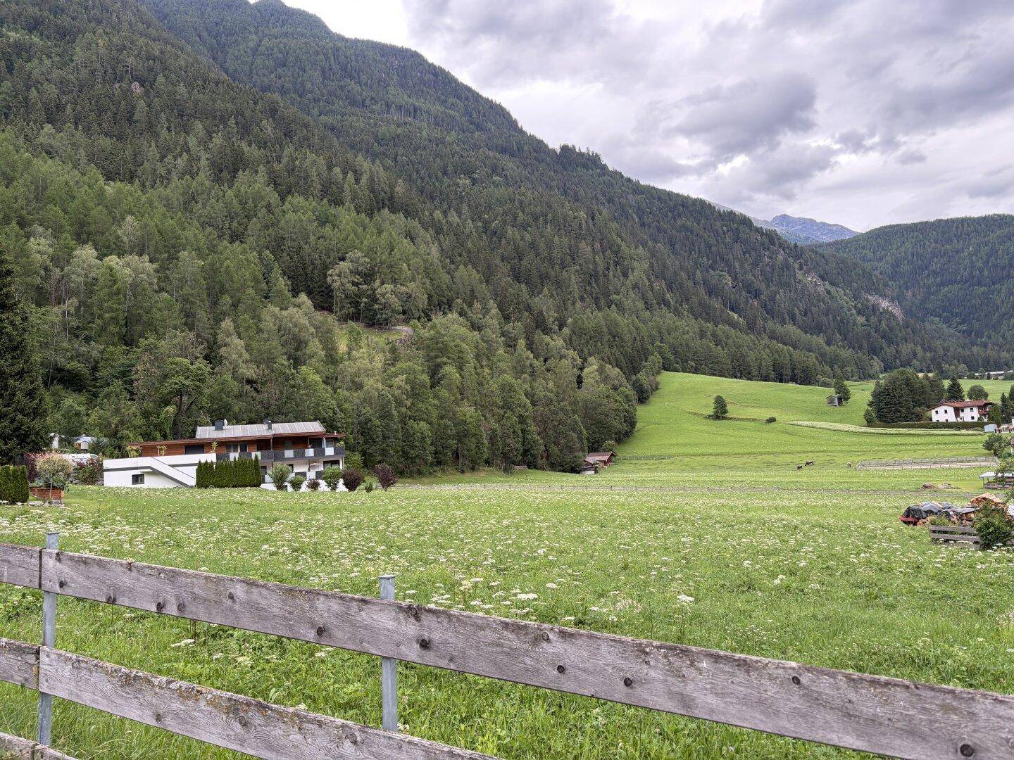 Immobilie eingebettet in eine malerische Naturkulisse mit Bergen und grünen Feldern.