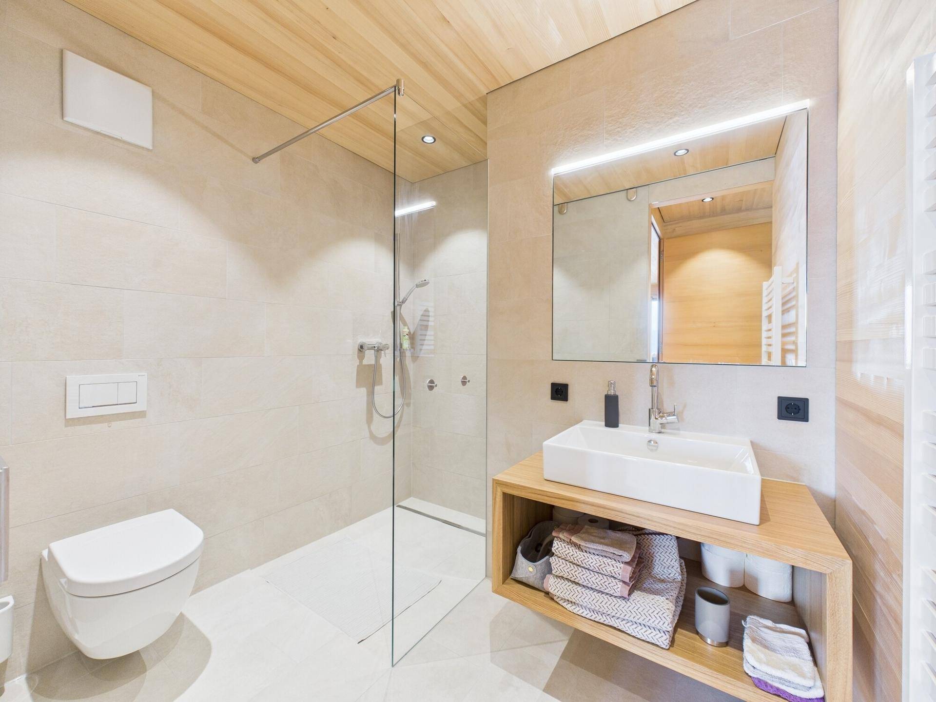 Modernes Badezimmer mit begehbarer Dusche, wandhängendem WC und Holzwaschtisch.