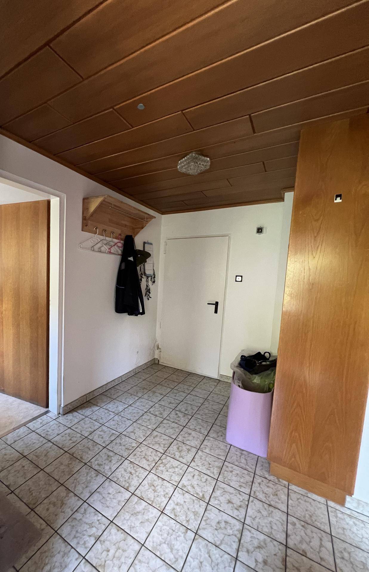 Eingangsbereich mit Holzdecke, Fliesenboden und Garderobe.