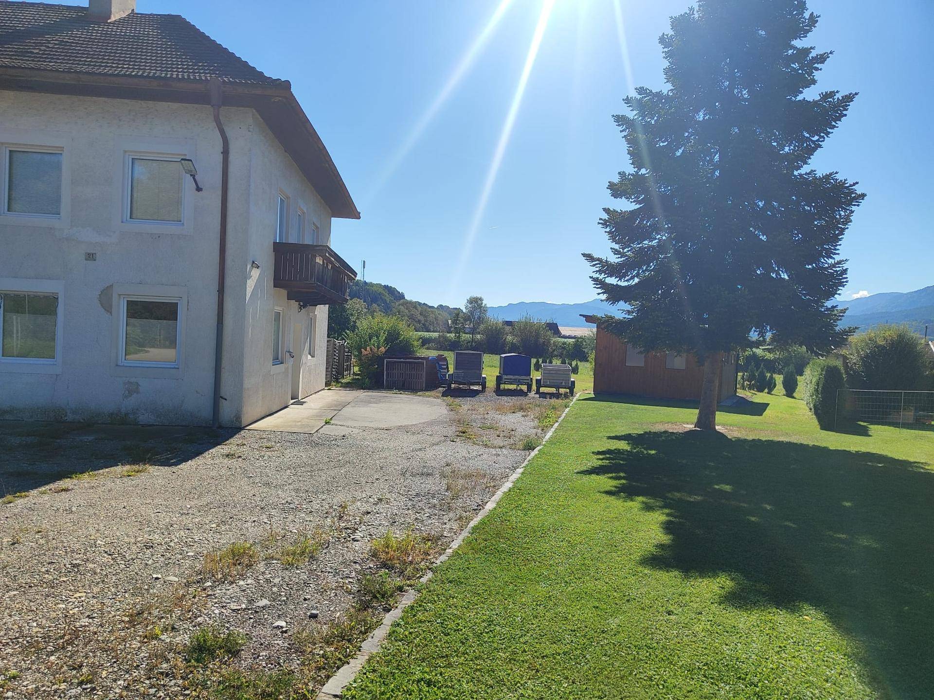 Großer Gartenbereich neben dem Haus mit Rasenfläche und Blick auf die weite Landschaft an einem sonnigen Tag.
