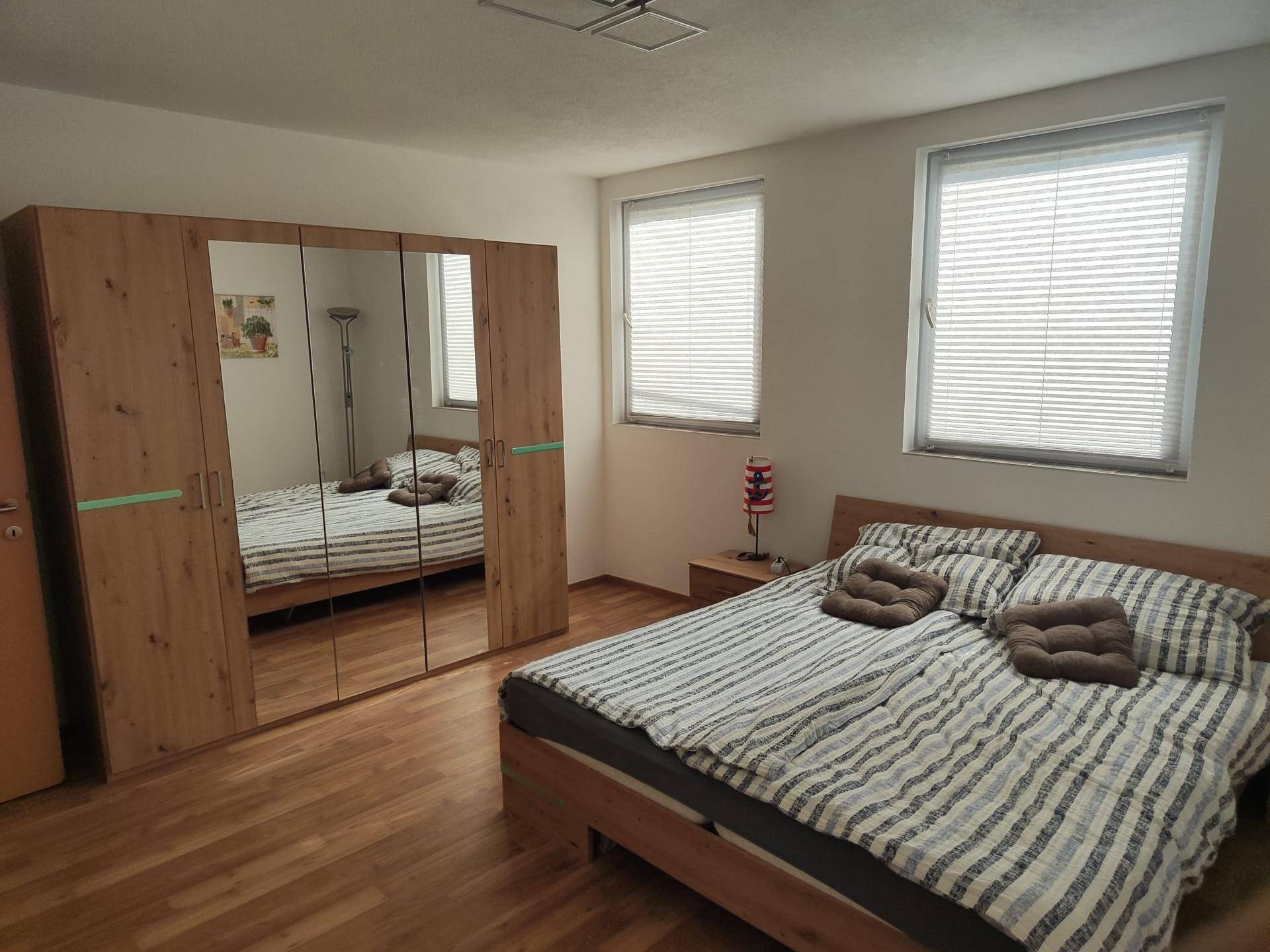 Geräumiges Schlafzimmer mit Doppelbett, großem Spiegelschrank und Laminatboden.